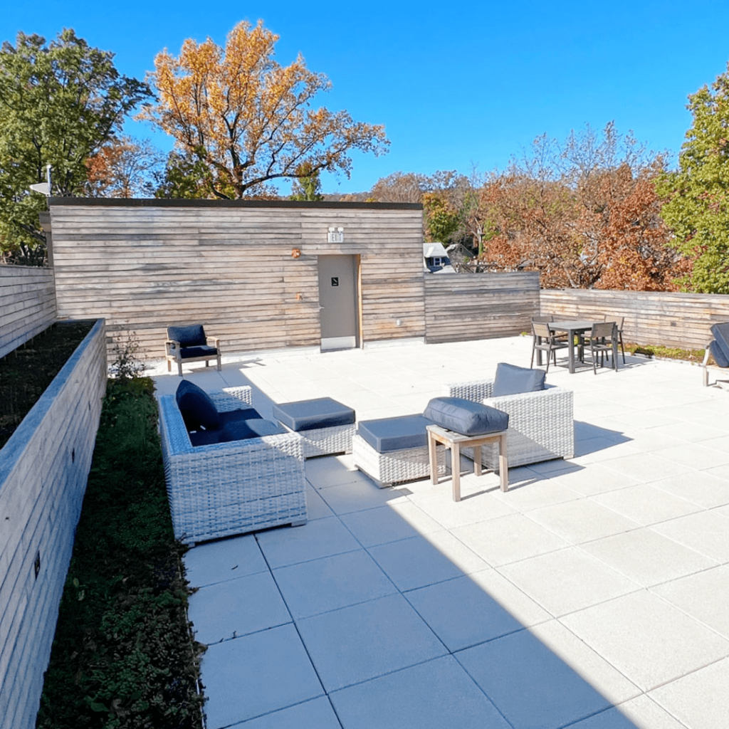 A spacious rooftop patio with wicker furniture and a scenic view of autumn trees, featuring modern outdoor seating areas.